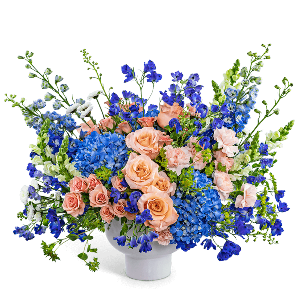 Peach roses and blue flowers in a white vase