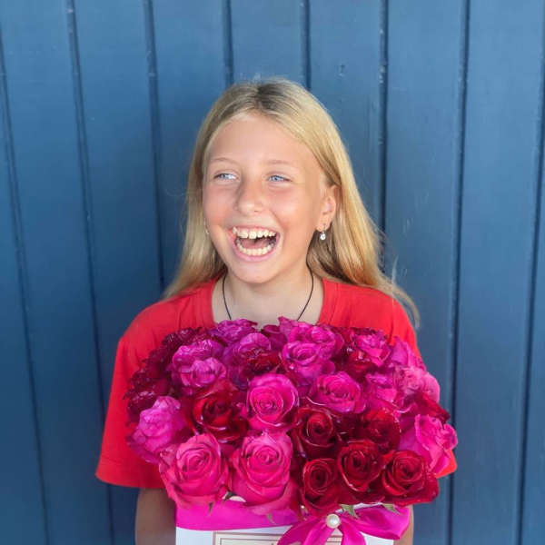 Girl holding a box of pink and red roses with a ribbon