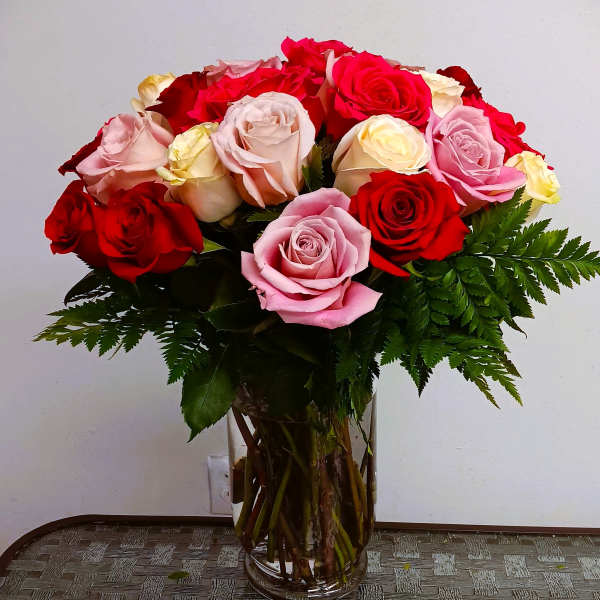 Bouquet of red, pink, and cream roses in a clear glass vase