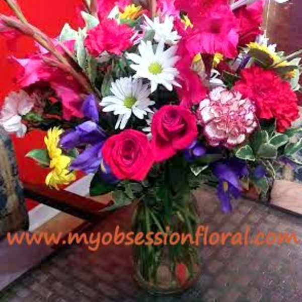 Bright mixed bouquet with pink roses and white daisies in a glass vase