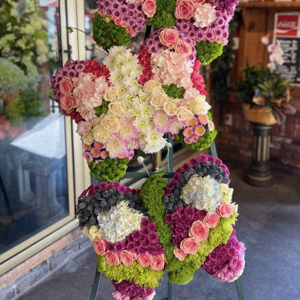 Butterfly-shaped floral standing display in pink, white, and green