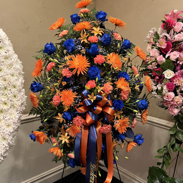 Standing floral wreath with orange, blue, and coral blooms on an easel
