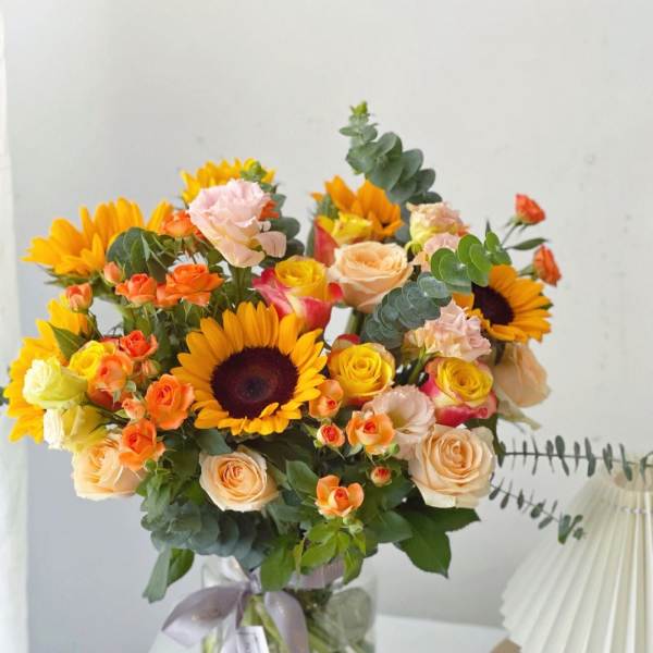 Bouquet of sunflowers and peach roses in a glass vase