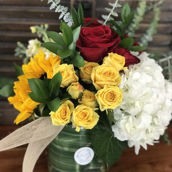 Bouquet of red and yellow roses with white hydrangeas in a glass vase
