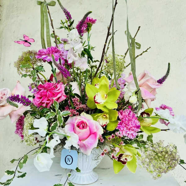 Pink and white floral arrangement in a white vase with tall branches