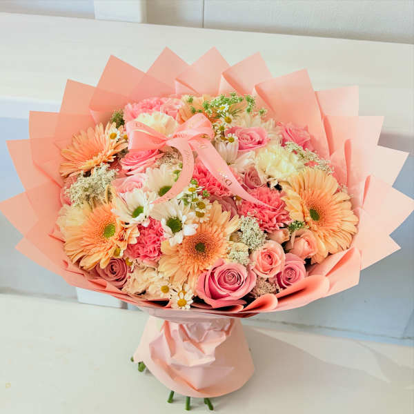 Pink and peach mixed bouquet wrapped in pastel paper