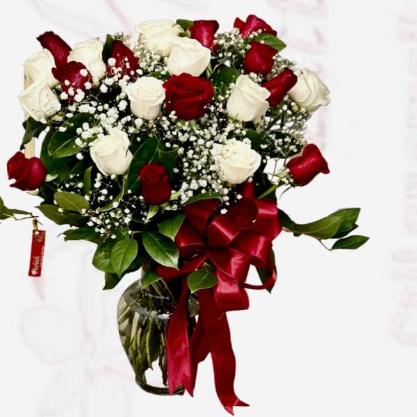 Bouquet of red and white roses in a glass vase with a red ribbon