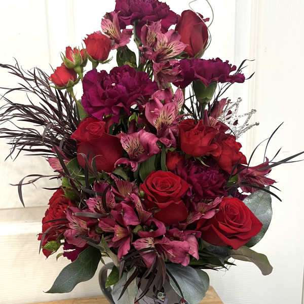Bouquet of red roses, pink alstroemeria, and dark carnations in a decorative vase