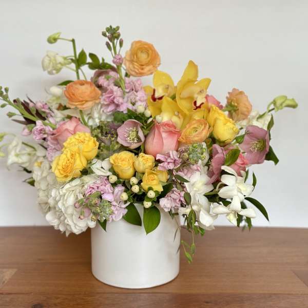 Mixed bouquet of yellow, pink, and white flowers in a white vase