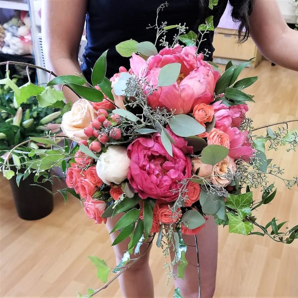 Handheld bouquet of pink peonies and roses with greenery