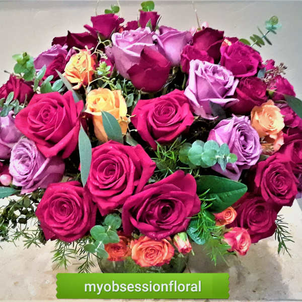 Bouquet of pink, purple, and orange roses in a glass vase