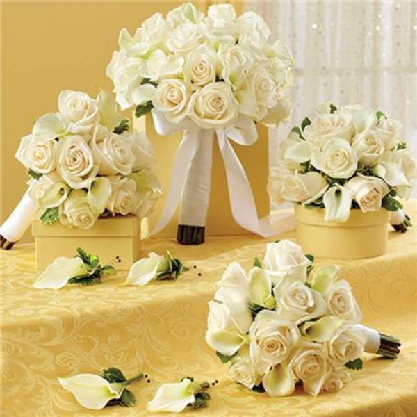 White rose and calla lily bouquets with ribbon on a yellow table