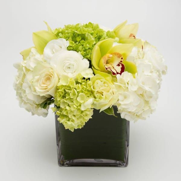 White and pale yellow flowers arranged in a square glass vase
