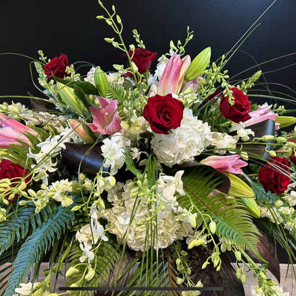 Large floral arrangement with red roses, pink lilies, and white blooms