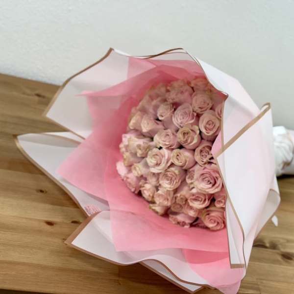Bouquet of pale pink roses wrapped in white and pink paper