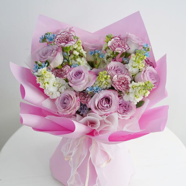 Pink bouquet of roses and carnations wrapped in pink paper