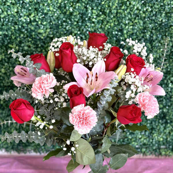 Bouquet of red roses, pink lilies, and carnations in a white vase
