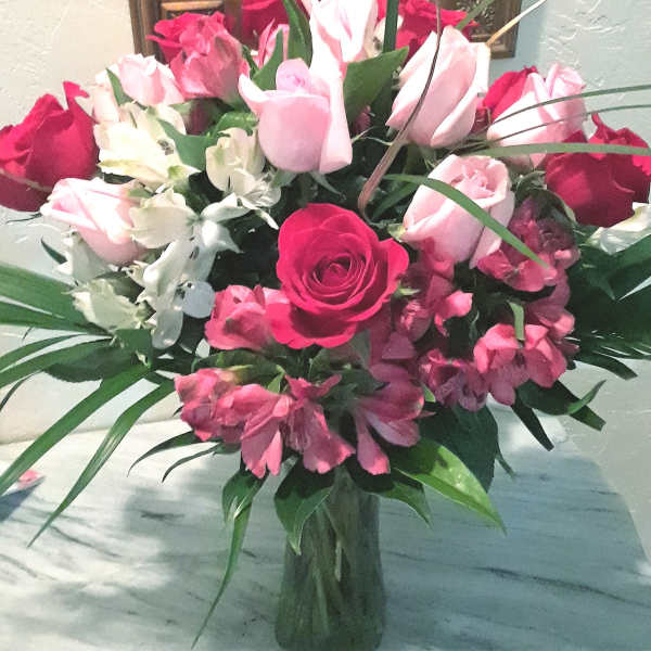 Bouquet of pink and red roses with white flowers in a glass vase