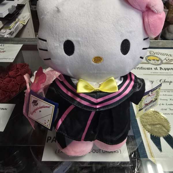 Hello Kitty plush in a graduation outfit with a small rose bouquet
