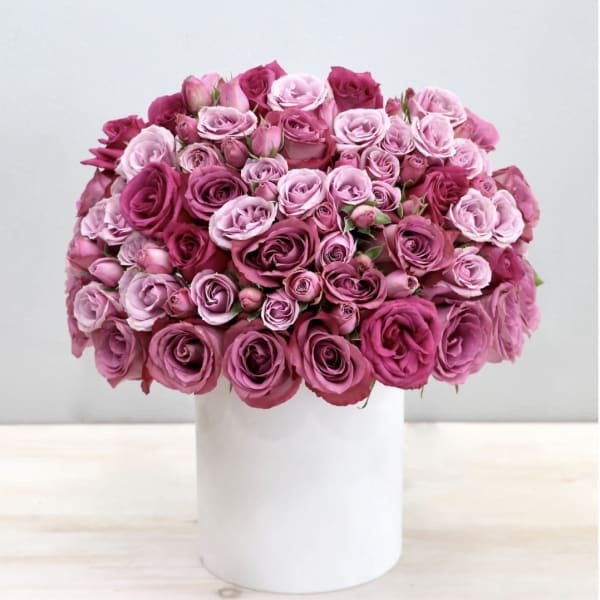Round bouquet of pink and magenta roses in a white vase