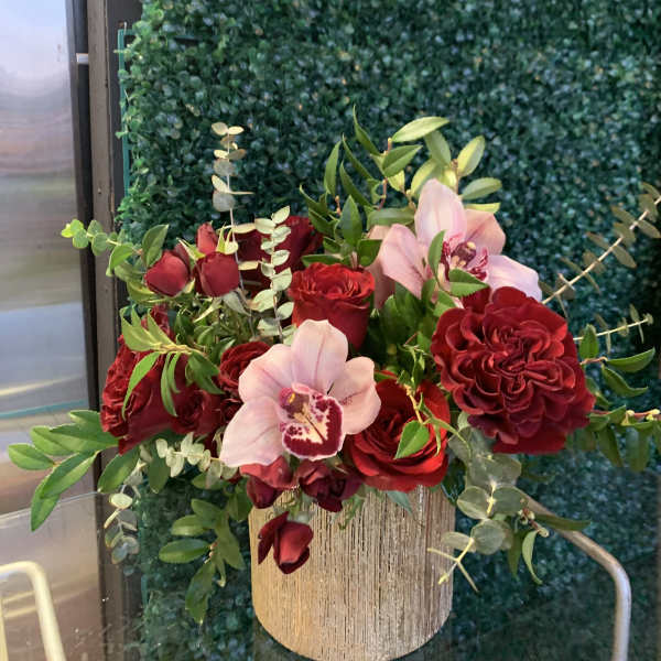 Red roses and pink orchids arranged in a gold vase