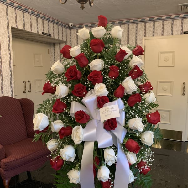 Standing spray of red and white roses with a white ribbon bow