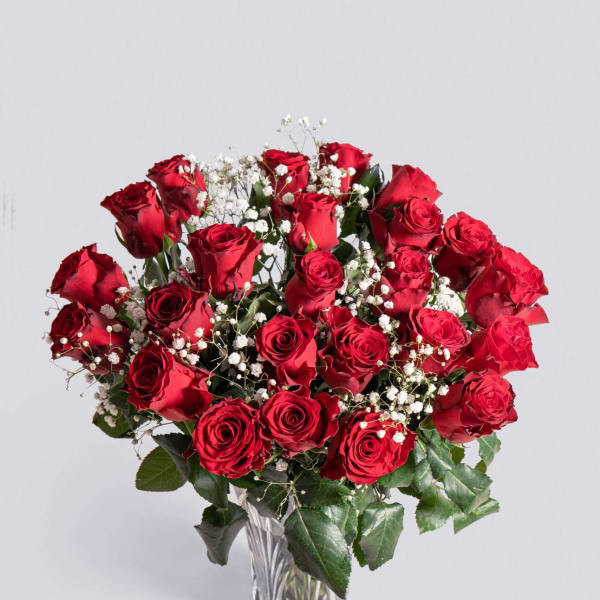 Bouquet of red roses with white baby's breath in a clear glass vase