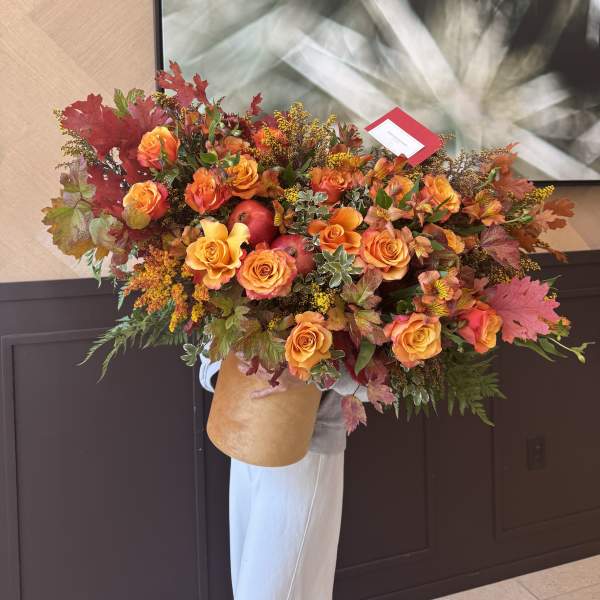Large bouquet of orange roses with autumn leaves and red apples