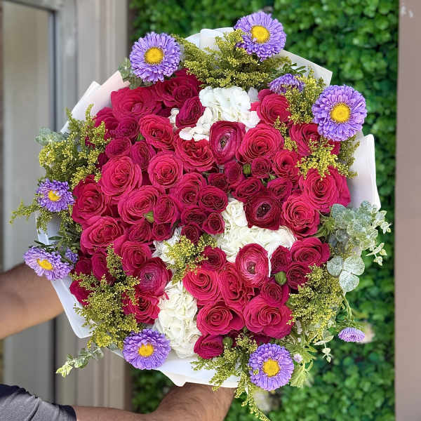 Bouquet of pink roses, white flowers, and purple daisies