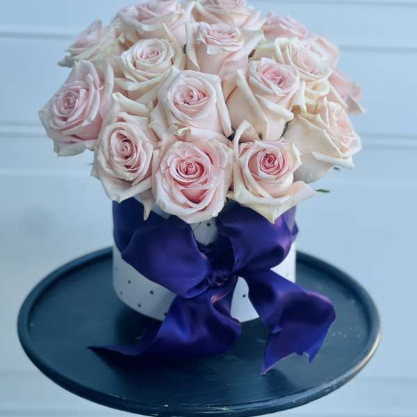 Bouquet of pale pink roses tied with a purple ribbon