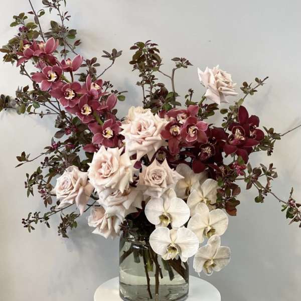 Bouquet of pale roses and orchids in a clear glass vase