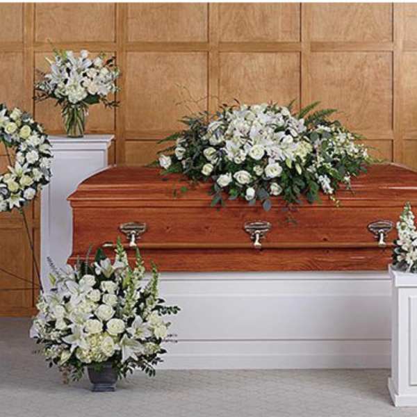 White funeral floral arrangements around a casket in a chapel