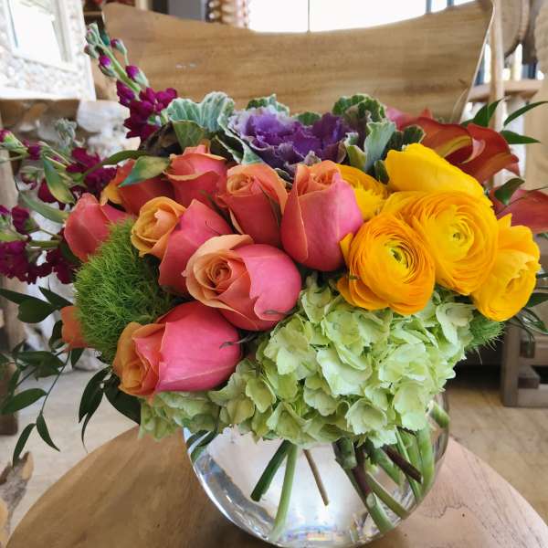 Mixed bouquet of roses, ranunculus, hydrangea, and calla lilies in a glass vase