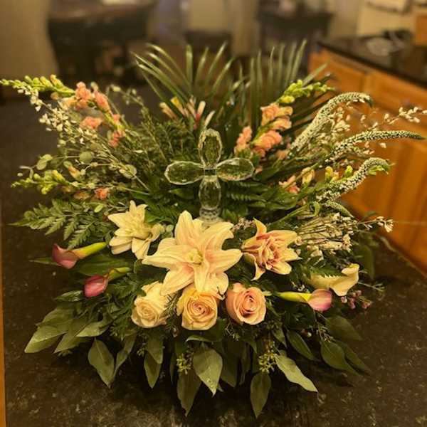Large floral arrangement with lilies, roses, and mixed greenery in a low container