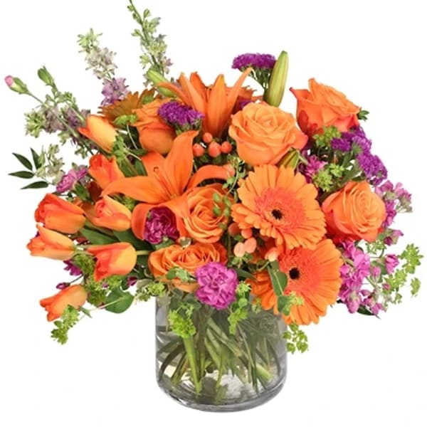 Orange and purple mixed flower arrangement in a glass vase