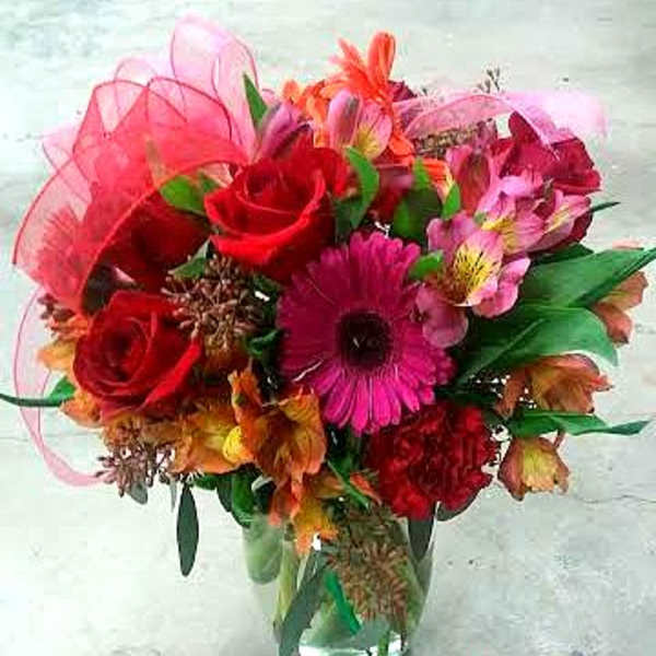 Bouquet of red roses and pink gerbera daisies in a glass vase