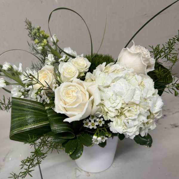 White roses and hydrangeas arranged in a white vase