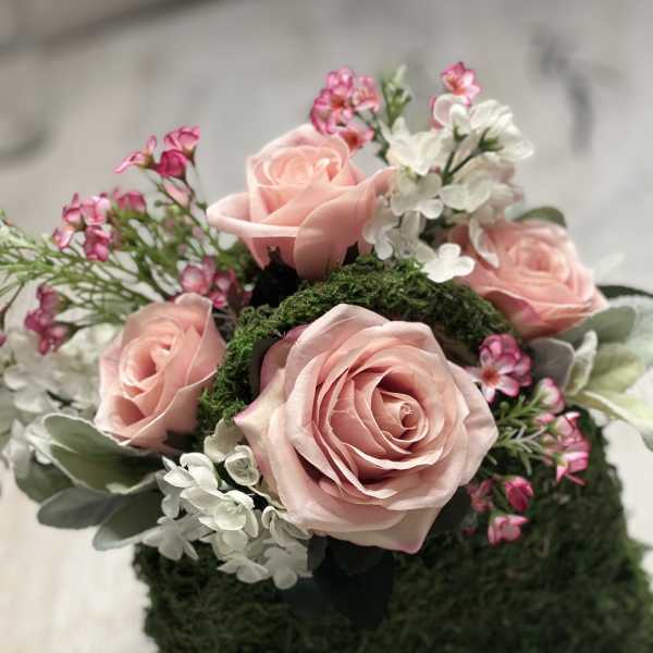 Pink roses with white and pink filler flowers in a moss-covered heart shape