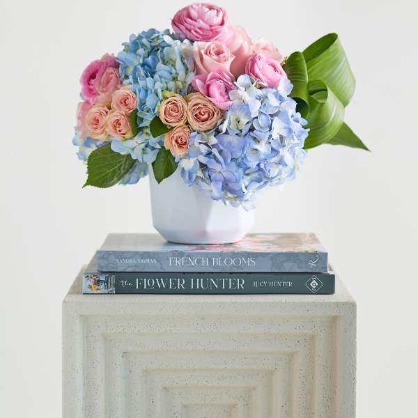 Pink roses and blue hydrangeas in a white vase