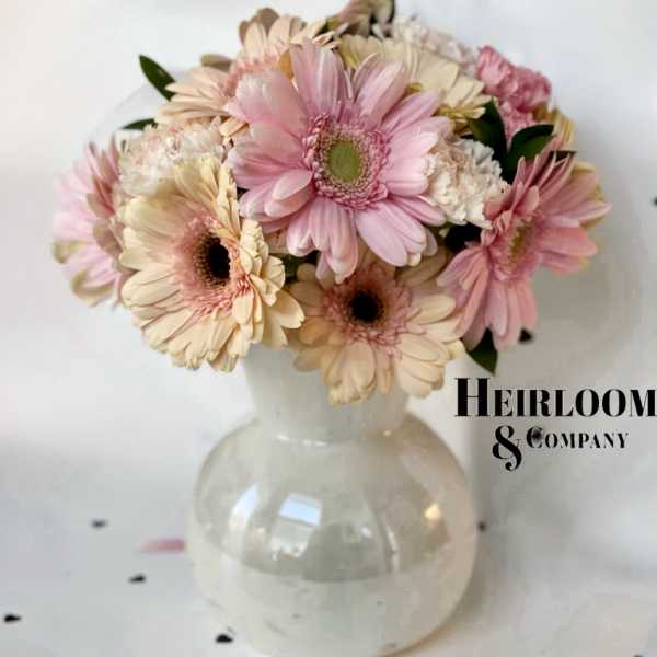 Pink and cream gerbera daisies arranged in a clear glass vase