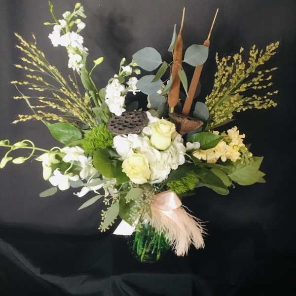 Mixed floral arrangement in a green vase with white blooms and tall seed heads