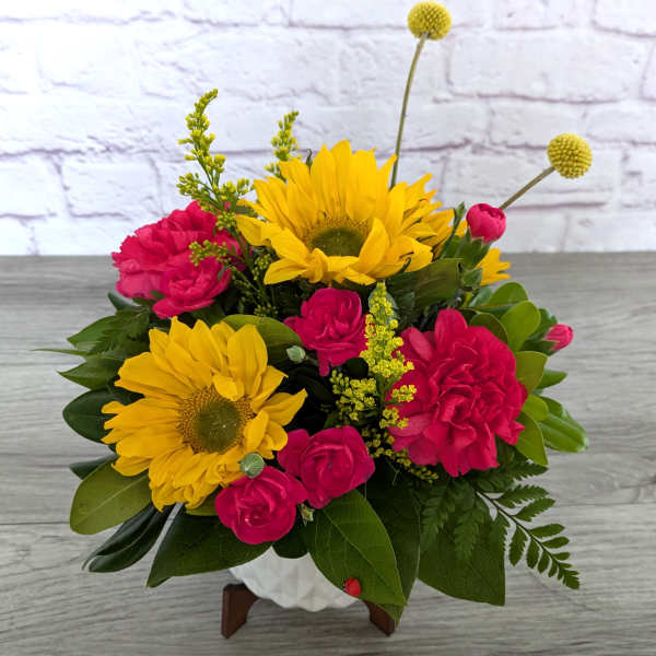 Bouquet of yellow sunflowers and hot pink roses in a white vase