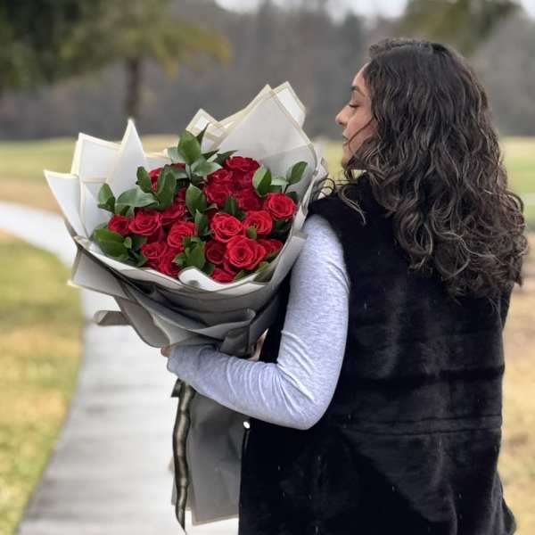 Woman holding a bouquet of red roses wrapped in paper