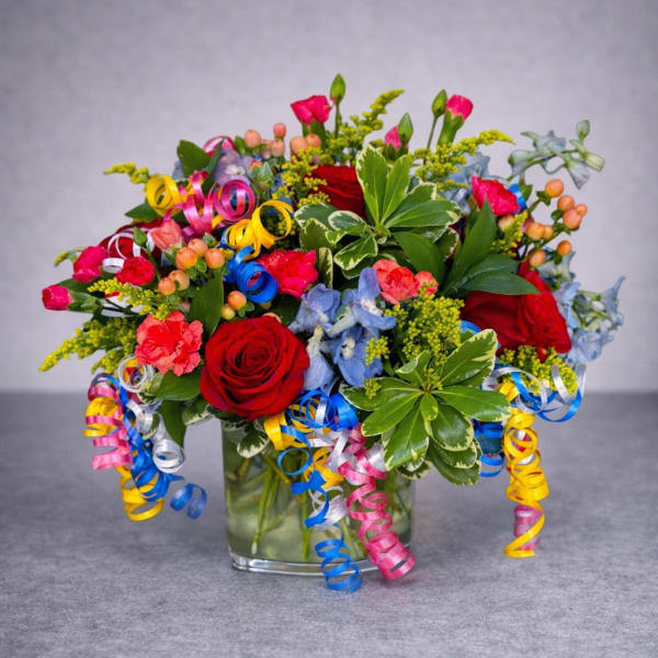 Colorful bouquet of roses and mixed flowers in a glass vase with ribbon curls