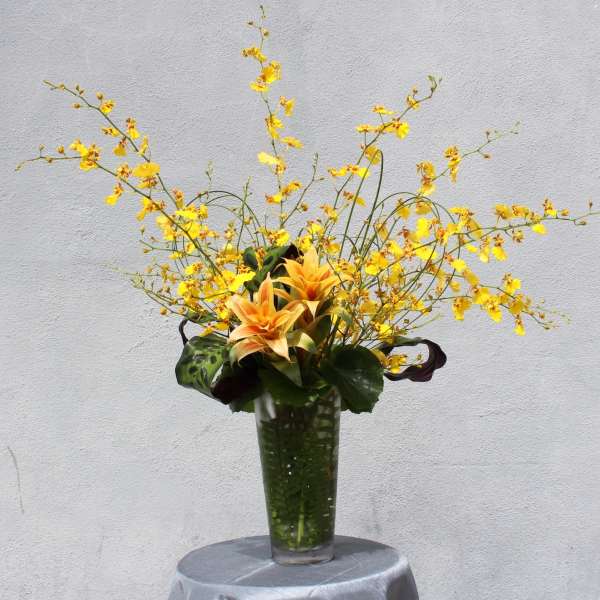 Tall yellow floral arrangement in a clear glass vase