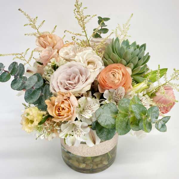 Mixed pastel bouquet in a glass vase with eucalyptus and succulents