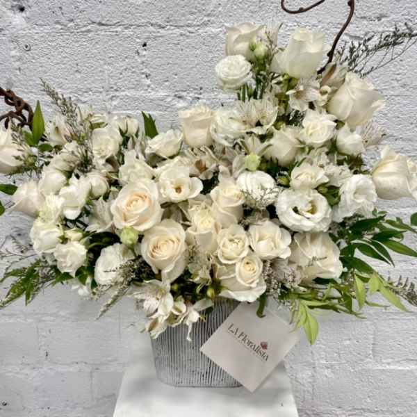 White rose and orchid arrangement in a striped container