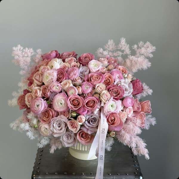 Pink and blush rose bouquet in a white vase with feathery accents