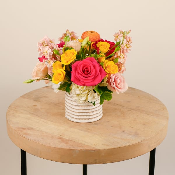 Mixed bouquet of roses and pastel flowers in a white ribbed vase