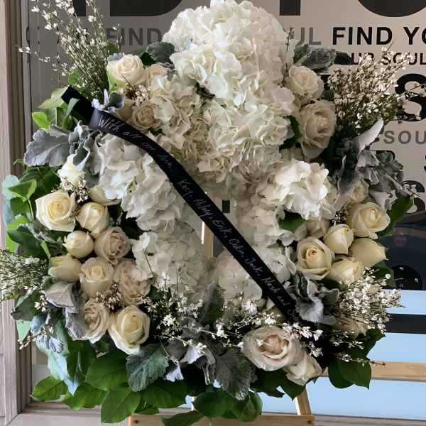 White floral wreath with roses and hydrangeas on an easel